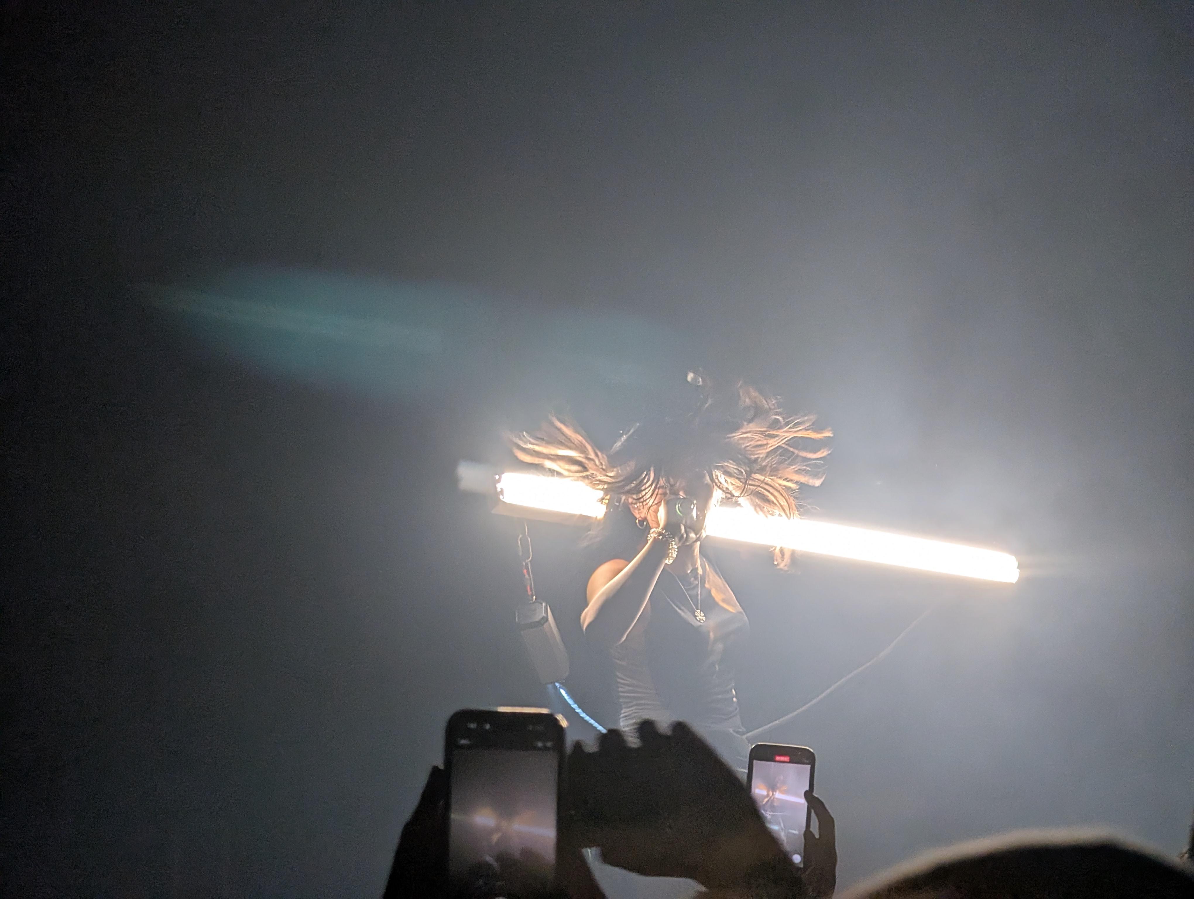 underscores holding a long light behind her